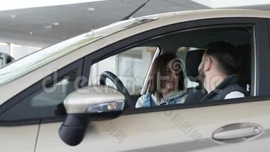 参观汽车经销商。 漂亮的一家人坐在他们的<strong>新</strong>车里，在说话和微笑。 年轻人用手指